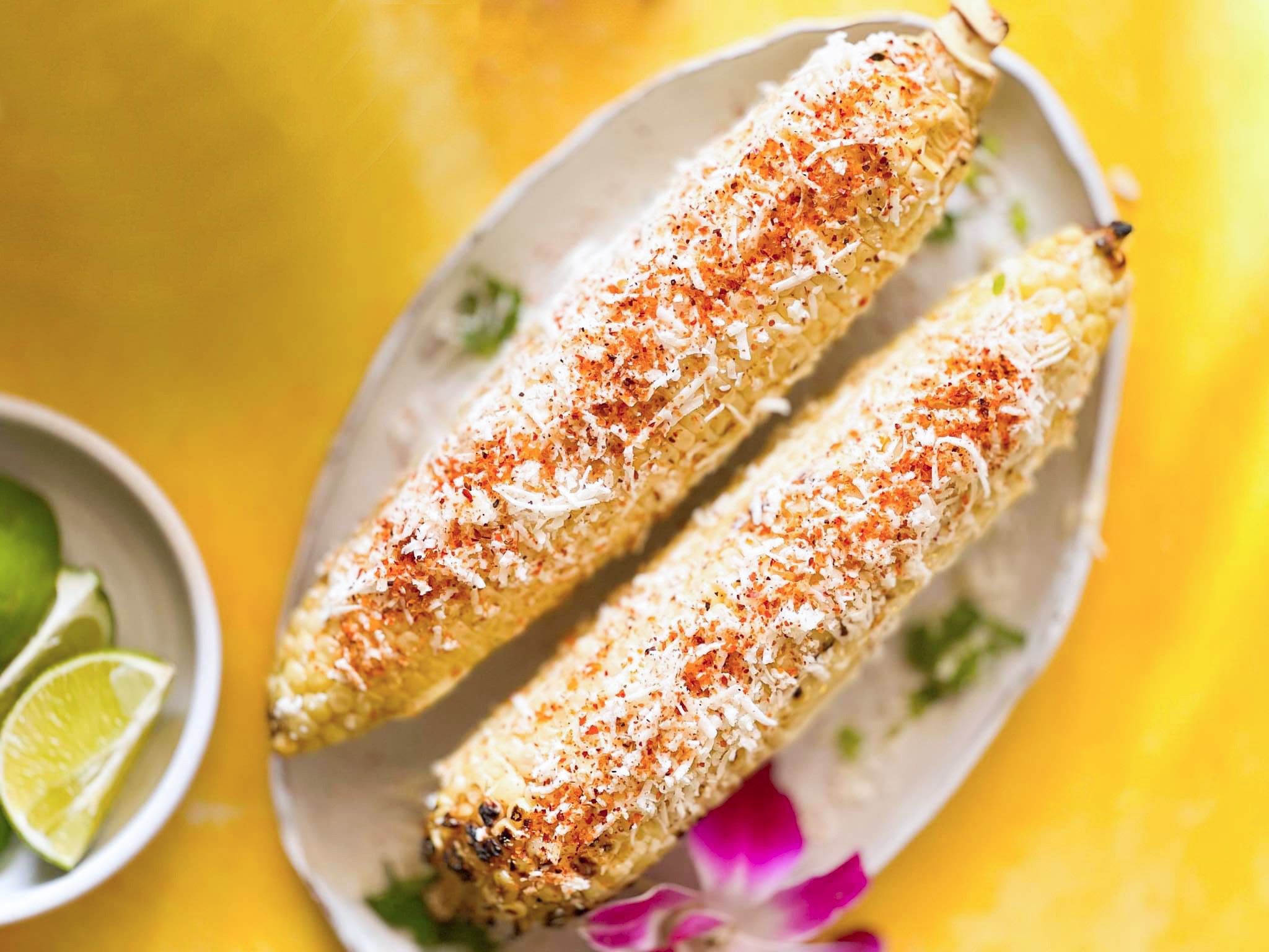 8. aug_mexican_street_corn Mexican Street Corn with sliced lime garnish on yellow table